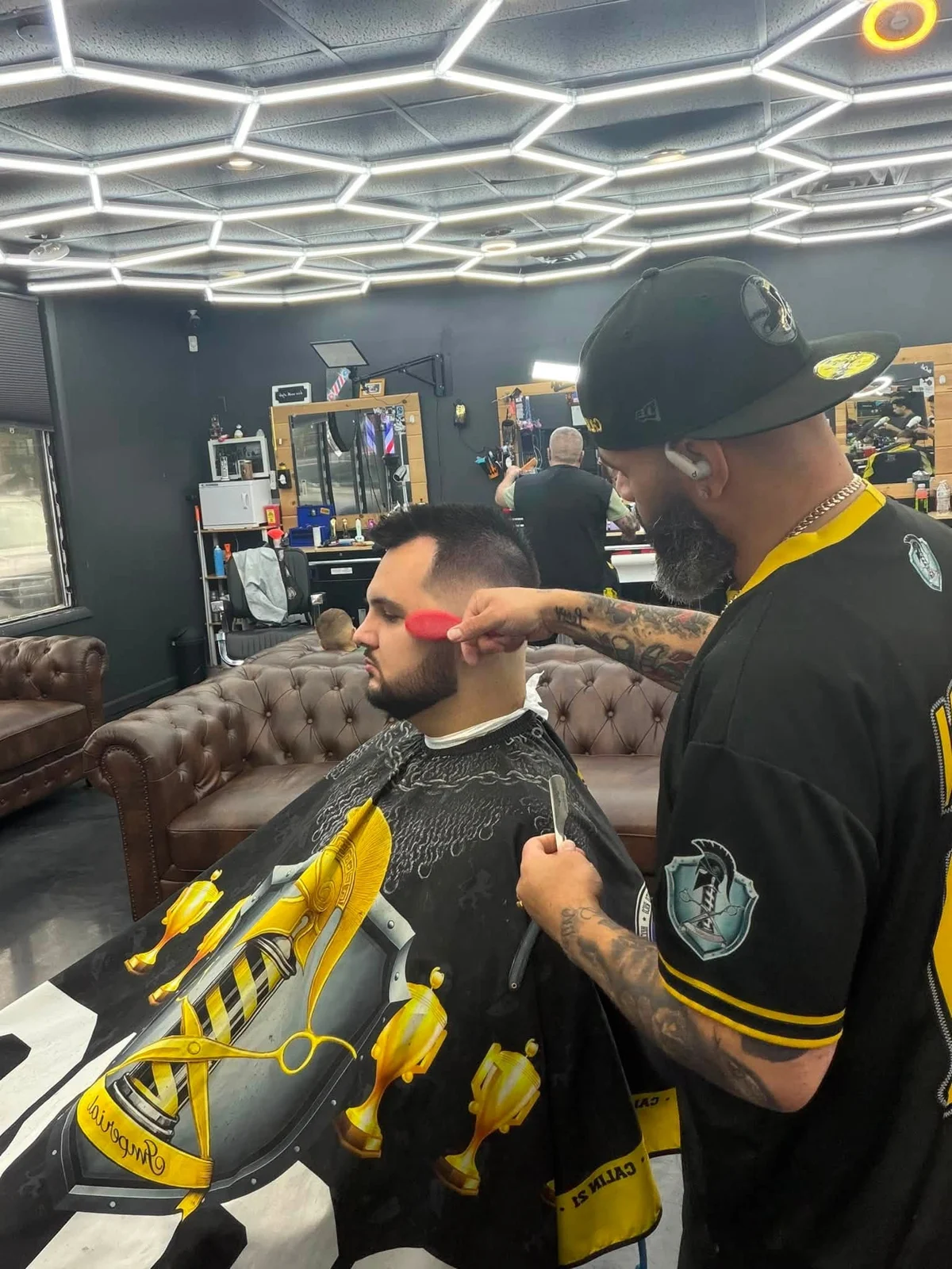 Barber brushing loose hair from a customer’s fade at Imperial Barbershop.