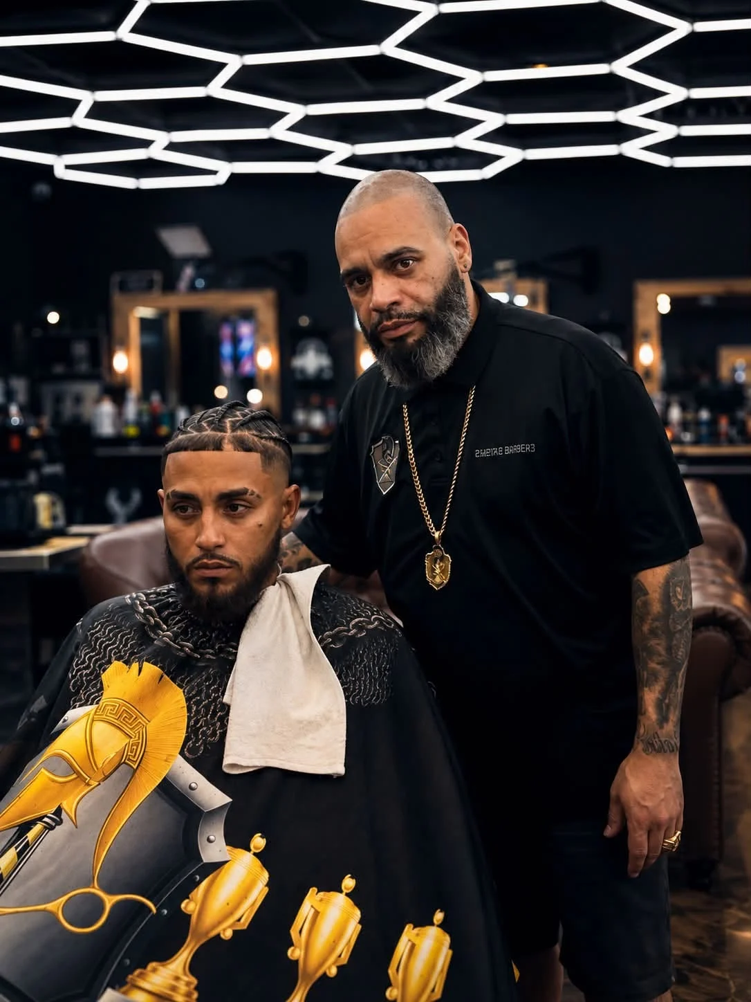 Barber standing beside a seated customer at Imperial Barbershop.